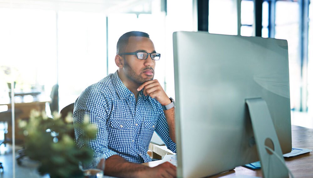 Business man, thinking and computer at desk in office for online research, reading email or report. Male entrepreneur person with internet connection for feedback, review and focus on project